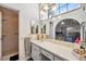 Bright bathroom with large mirror, vanity sink, shower stall, and arched window allowing natural light at 8137 Greenside Ln, Hudson, FL 34667
