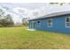 Nice backyard showcasing a lush lawn and a blue home with sliding glass doors and patio at 9510 Xenia St, New Port Richey, FL 34654