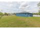 Sprawling backyard showcasing its lush green lawn and a blue painted home in the distance at 9510 Xenia St, New Port Richey, FL 34654