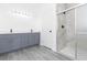 Bathroom featuring modern gray cabinets, neutral paint, updated lighting, and glass enclosed shower at 9510 Xenia St, New Port Richey, FL 34654