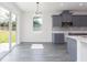Modern kitchen with gray cabinetry, white backsplash, stainless appliances and sliding door at 9510 Xenia St, New Port Richey, FL 34654