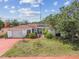 Charming single-story home with a well-manicured lawn, mature landscaping, and a vibrant red driveway at 1629 Dartmouth Dr, Holiday, FL 34691