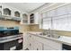 This is a kitchen with a light blue gas stove, beige backsplash, and a double sink with a window above at 1629 Dartmouth Dr, Holiday, FL 34691