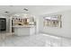 Bright, open-concept living space with tile flooring flowing into kitchen with breakfast bar seating at 1629 Dartmouth Dr, Holiday, FL 34691