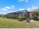 A view of the screened-in pool and lanai from the perfectly manicured backyard of the home at 2025 E View Dr, Sun City Center, FL 33573