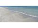Expansive beach view with clear, shallow water gently lapping against the sandy shore at 3100 Gulf Blvd # 134, Belleair Beach, FL 33786