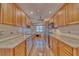 Galley kitchen featuring wood cabinets, granite countertops, stainless steel appliances and tile backsplash at 3100 Gulf Blvd # 134, Belleair Beach, FL 33786