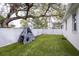 Artificial grass backyard featuring a climbing structure, and a large shade tree, perfect for outdoor recreation at 3405 W Cherry St, Tampa, FL 33607