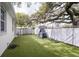 Spacious backyard with artificial grass, a climbing structure, and mature trees, ideal for outdoor entertainment at 3405 W Cherry St, Tampa, FL 33607