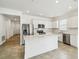 Open-concept kitchen with white cabinets, stainless steel appliances, and a quartz island overlooking living area at 4275 Big Sky Dr, Spring Hill, FL 34604