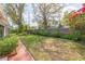 Spacious backyard showcasing green lawn, mature trees, lush landscaping, brick borders, and a wooden fence at 4517 S Renellie Dr, Tampa, FL 33611