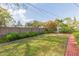 Grassy backyard framed by mature trees, privacy fence, border plants, and a brick-lined walkway at 4517 S Renellie Dr, Tampa, FL 33611