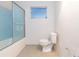This bathroom shows blue wall tiles, a white toilet, and a window that allows light to flood in at 4517 S Renellie Dr, Tampa, FL 33611