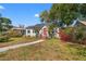 Charming bungalow-style home featuring a red front door, lush landscaping, and a curved walkway at 511 27Th N Ave, St Petersburg, FL 33704