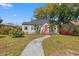 Charming bungalow-style home featuring a red front door, lush landscaping, and a curved walkway at 511 27Th N Ave, St Petersburg, FL 33704