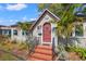 Inviting front porch with brick steps, iron railing, and a red front door framed by palm trees at 511 27Th N Ave, St Petersburg, FL 33704