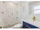 Stylish bathroom featuring a walk-in shower with marble tile and blue vanity at 5402 31St S Ave, Gulfport, FL 33707