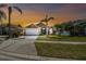 Inviting home exterior with a manicured lawn, palm trees, and a two-car garage at dusk at 7222 Sharpsburg Blvd, New Port Richey, FL 34653