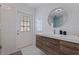 Tastefully renovated bathroom features a door leading outside, modern vanity, a sink, and a round mirror at 7998 Causeway N Blvd, St Petersburg, FL 33707