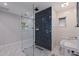 Modern bathroom with seamless glass shower and blue mosaic tile, toilet, sink and window at 7998 Causeway N Blvd, St Petersburg, FL 33707