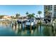 Picturesque boat dock featuring multiple boats, surrounded by lush palm trees and waterfront homes at 1651 Sand Key Estates Ct # 53, Clearwater, FL 33767