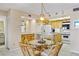 Open-concept dining area next to the kitchen featuring a glass-top table with wicker chairs, under decorative lighting at 1651 Sand Key Estates Ct # 53, Clearwater, FL 33767