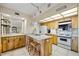 Open kitchen featuring wood cabinetry, granite counters, stainless appliances, breakfast bar and tile flooring at 1651 Sand Key Estates Ct # 53, Clearwater, FL 33767