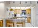 Cozy kitchen with wood cabinetry, stainless steel appliances, granite countertops and a breakfast bar with stools at 1651 Sand Key Estates Ct # 53, Clearwater, FL 33767