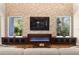 Living room view of brick wall, fireplace, entertainment center and large windows overlooking trees at 17801 Saint Lucia Isle Dr, Tampa, FL 33647