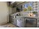 Outdoor kitchen features a grill, stainless steel appliances, stylish tile backsplash, and a stone counter at 17801 Saint Lucia Isle Dr, Tampa, FL 33647