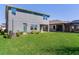 Spacious backyard featuring lush green lawn, a covered patio, and a partial view of an adjacent screened-in pool area at 17802 Everlong Dr, Land O Lakes, FL 34638