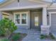 Inviting entrance with a gray door, stone accents, lush landscaping, and paved walkway at 17802 Everlong Dr, Land O Lakes, FL 34638