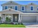 Charming two-story home featuring a gray exterior, well-manicured lawn, and inviting front entrance with a gray two-car garage at 17802 Everlong Dr, Land O Lakes, FL 34638