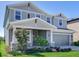Charming two-story home featuring a covered front porch, gray siding, a two car garage, and well-manicured landscaping at 17802 Everlong Dr, Land O Lakes, FL 34638