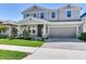Well-maintained two-story home with a gray exterior, landscaped yard, and paved driveway at 17802 Everlong Dr, Land O Lakes, FL 34638