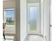 Hallway featuring a decorative glass door, neutral walls, tile flooring, and view of the landscaped yard at 17802 Everlong Dr, Land O Lakes, FL 34638