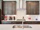Close-up of the kitchen with dark wood cabinets, stainless steel range hood, white countertops, and subway tile backsplash at 17802 Everlong Dr, Land O Lakes, FL 34638