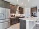 Bright kitchen featuring stainless steel appliances, dark wood cabinets, a range hood, and a white countertop island at 17802 Everlong Dr, Land O Lakes, FL 34638