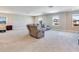 Spacious living room with plush carpeting, reclining gray sofa, and multiple windows offering plenty of natural light at 17802 Everlong Dr, Land O Lakes, FL 34638
