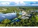 Aerial view showcasing community with pool, tennis courts, and lake amidst lush greenery at 19469 Autumn Oak Ln, Brooksville, FL 34601