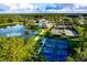 Aerial view showcasing the community pool, tennis courts, lake, and surrounding greenery at 19469 Autumn Oak Ln, Brooksville, FL 34601