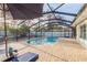 Enclosed pool area featuring a brick patio, lounge chairs, privacy fence, and a partial view of the surrounding yard at 2005 Harvard Ave, Dunedin, FL 34698