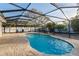 Enclosed swimming pool with a brick patio, sunshades, and surrounding landscaping at 2005 Harvard Ave, Dunedin, FL 34698