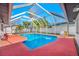 A refreshing screened pool with a red deck and white frame is showcased in this image at 2217 Stacy Ct, Dunedin, FL 34698