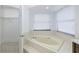 Bright bathroom features a soaking tub under a window and an open closet at 2233 Springwood W Cir, Clearwater, FL 33763