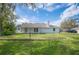 A beautifully landscaped backyard behind a white home with an open patio and bright white chimney at 2601 Savannah Dr, Plant City, FL 33563