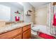 Bathroom with granite countertop, warm cherry cabinets, tub and shower, and red accents at 37850 Prairie Rose Loop, Zephyrhills, FL 33542
