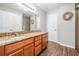 Bathroom with double sinks, granite countertops, wood cabinets, and tiled floors with a decorative wreath at 37850 Prairie Rose Loop, Zephyrhills, FL 33542