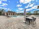 Community pool with lounge chairs, tables, and umbrellas under a blue, partly cloudy sky at 5027 Autumn Ridge Dr, Wesley Chapel, FL 33545
