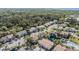 Aerial view of community with a pond, mature trees, and water views in the distance at 7631 Sailwinds Pass, Port Richey, FL 34668